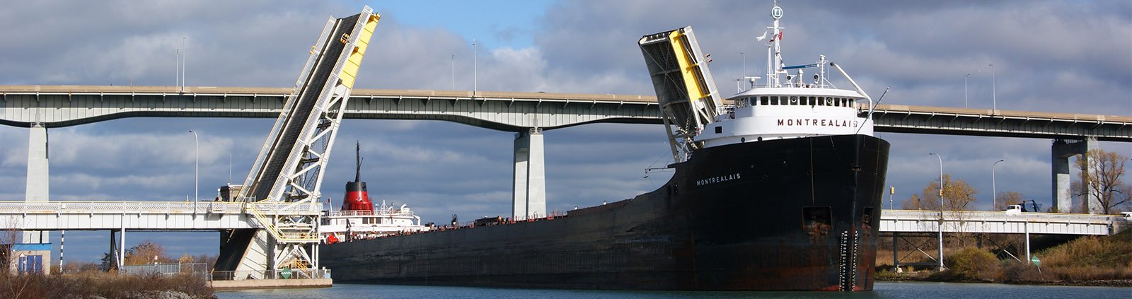 The ship Montrealis travels south on the Welland Canal under the open Homer Bridge.
