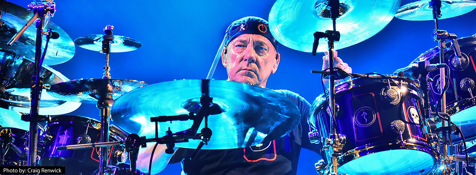 Neil Peart sits performing at his drum kit