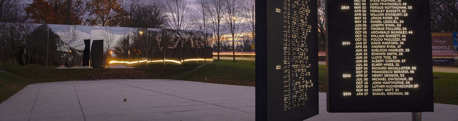 Names of fallen workers etched on a pillar with a mirrored wall behind them