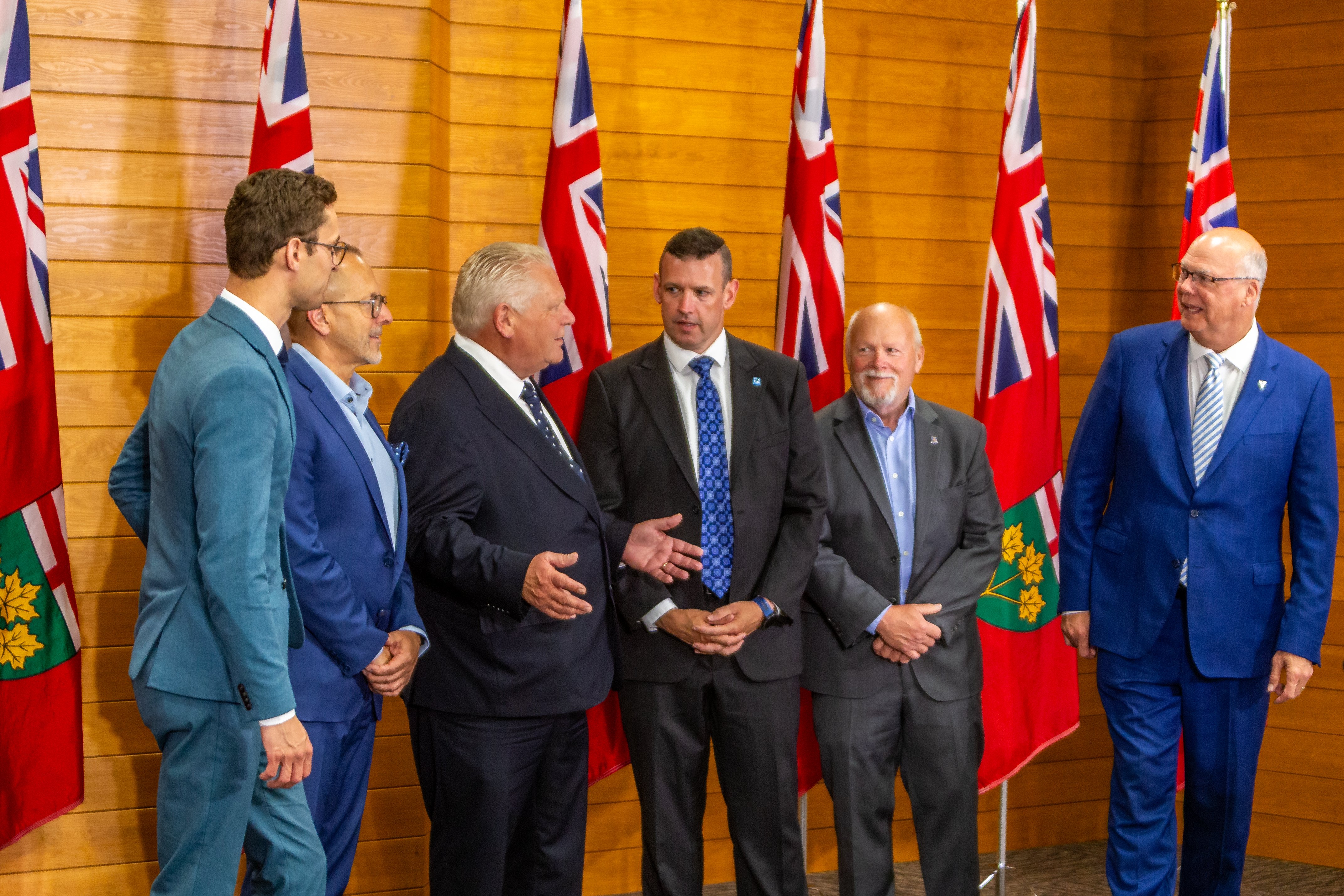 Premier Doug Ford stands at a podium speaking alongside local mayors and MPPs