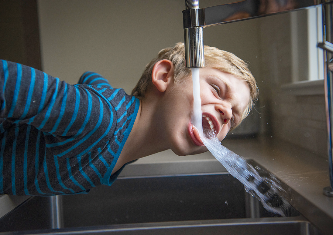 child drinking water from a tap