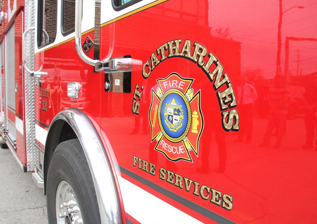 The side of a St. Catharines Fire Services fire truck, with a department log on the door