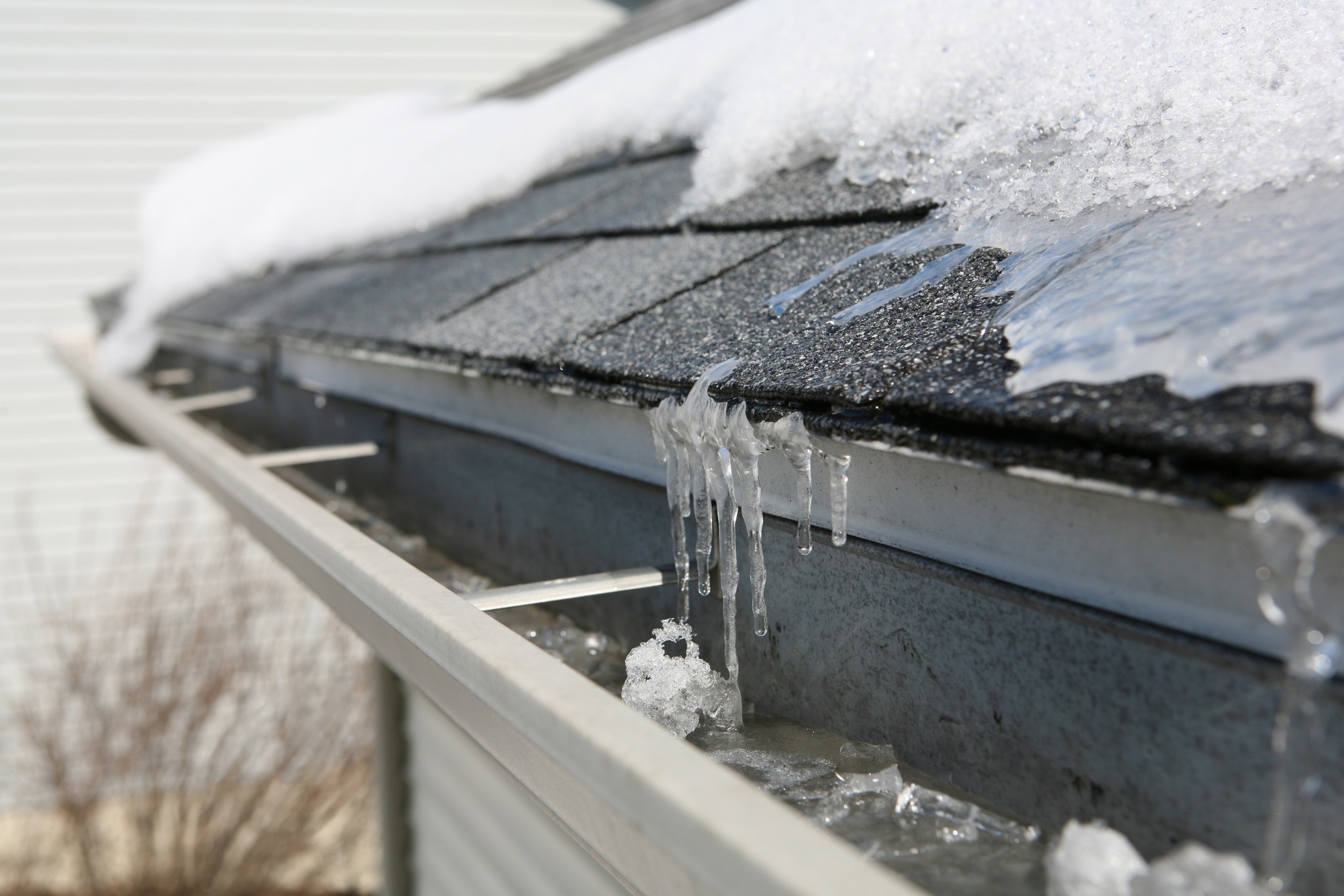 An eavestrough with melting snow and buildup