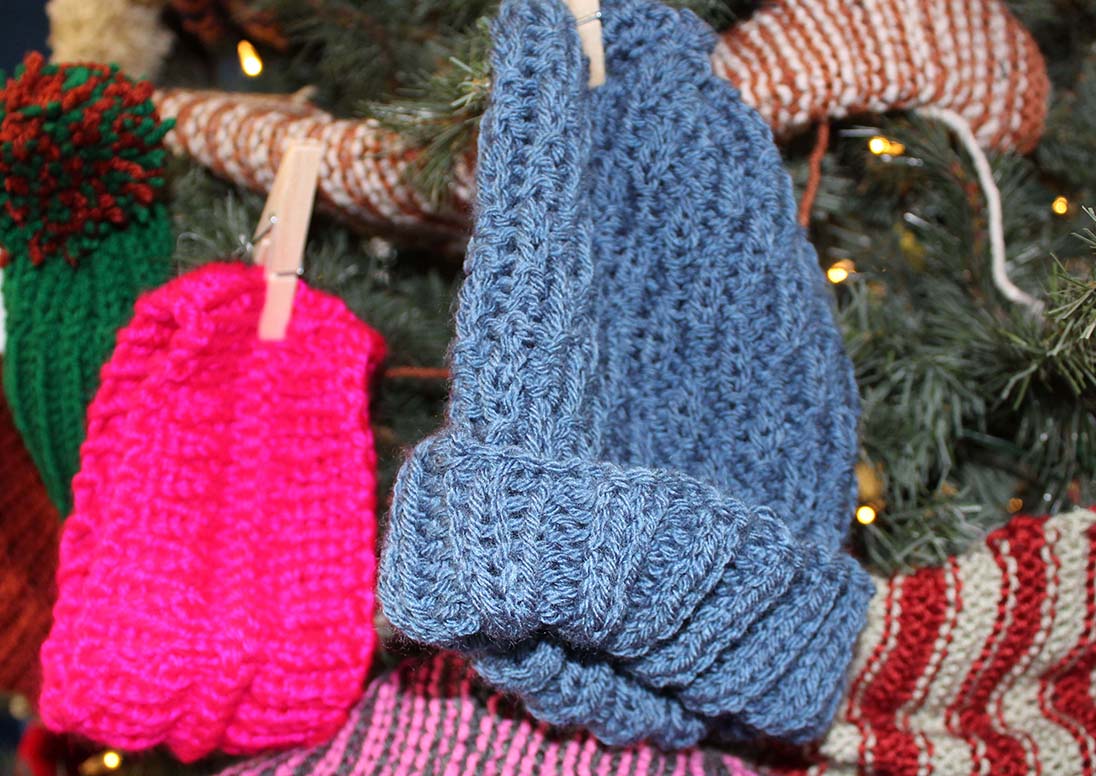 Donated knit scarves and hats hanging on the Museum Mitten Tree in December 2024.