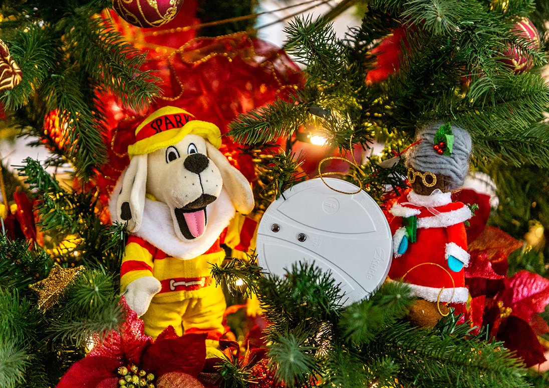 A toy Sparky the Fire Dog with a smoke alarm in a Christmas tree for the annual 12 Days of Holiday Fire Safety campaign.