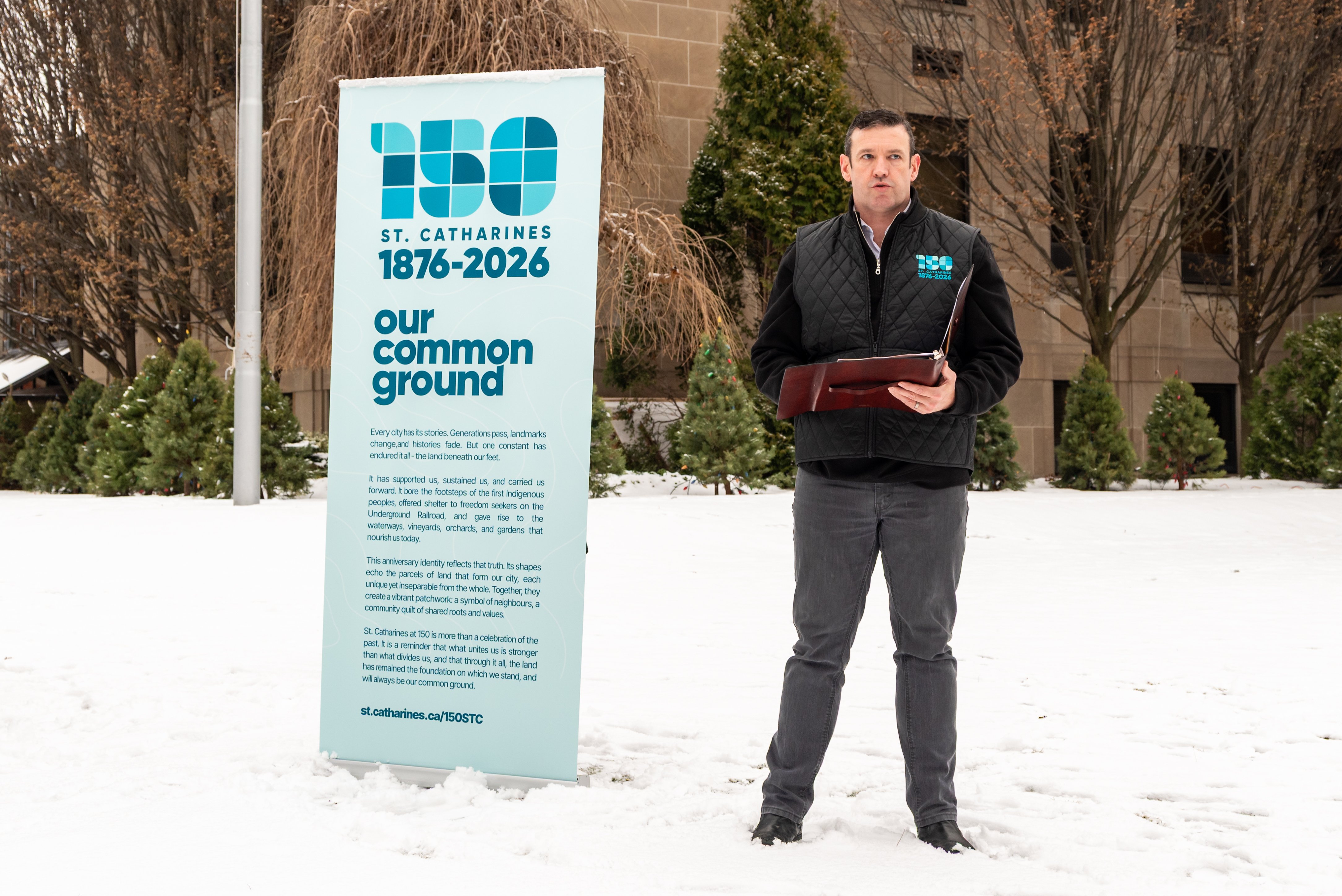 A man speaks next to a roll-up banner on snowy ground.