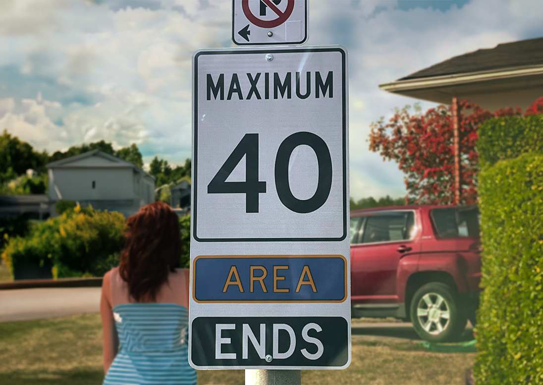 Photo of a woman standing beside a "Maximum 40 Area Begins" sign on a residential street.