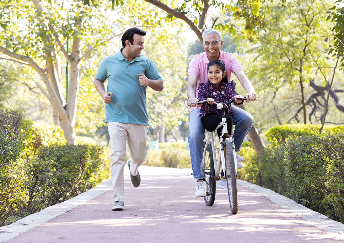 Photo of a man running beside a man riding a bike with a little girl on it