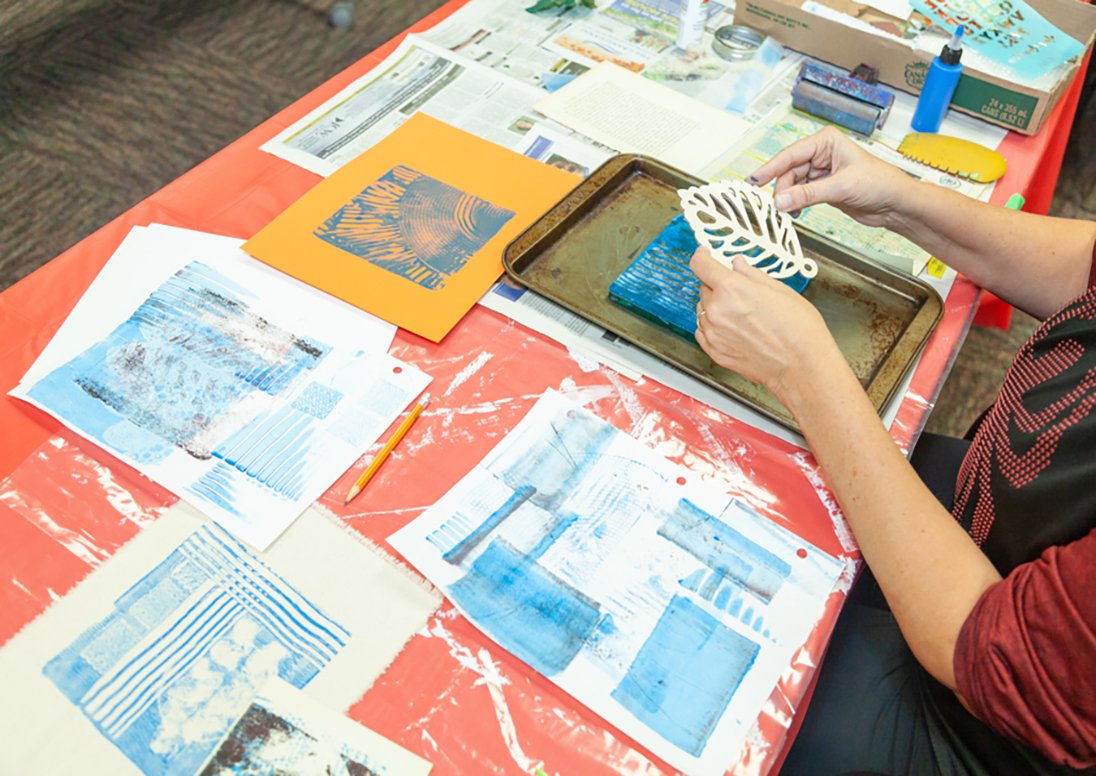 Artist working at a table with artwork on it. 