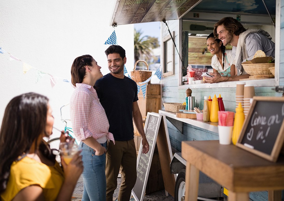 A couple looking at the menu and talking with food truck operators.