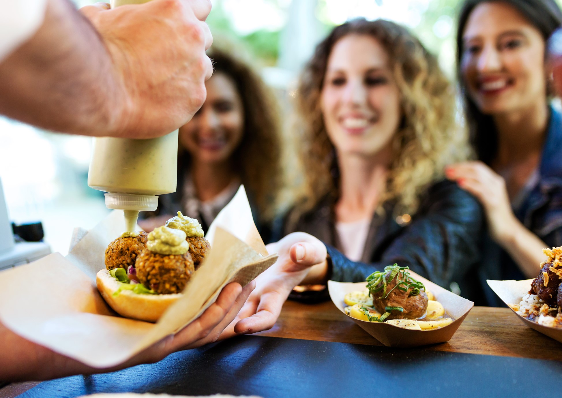 Food truck operator preparing a meal for three excited diners