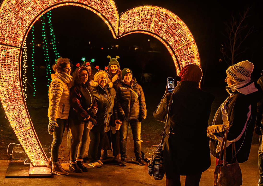 Women posing with a huge lit heart during Let It Glow opening night 2024.
