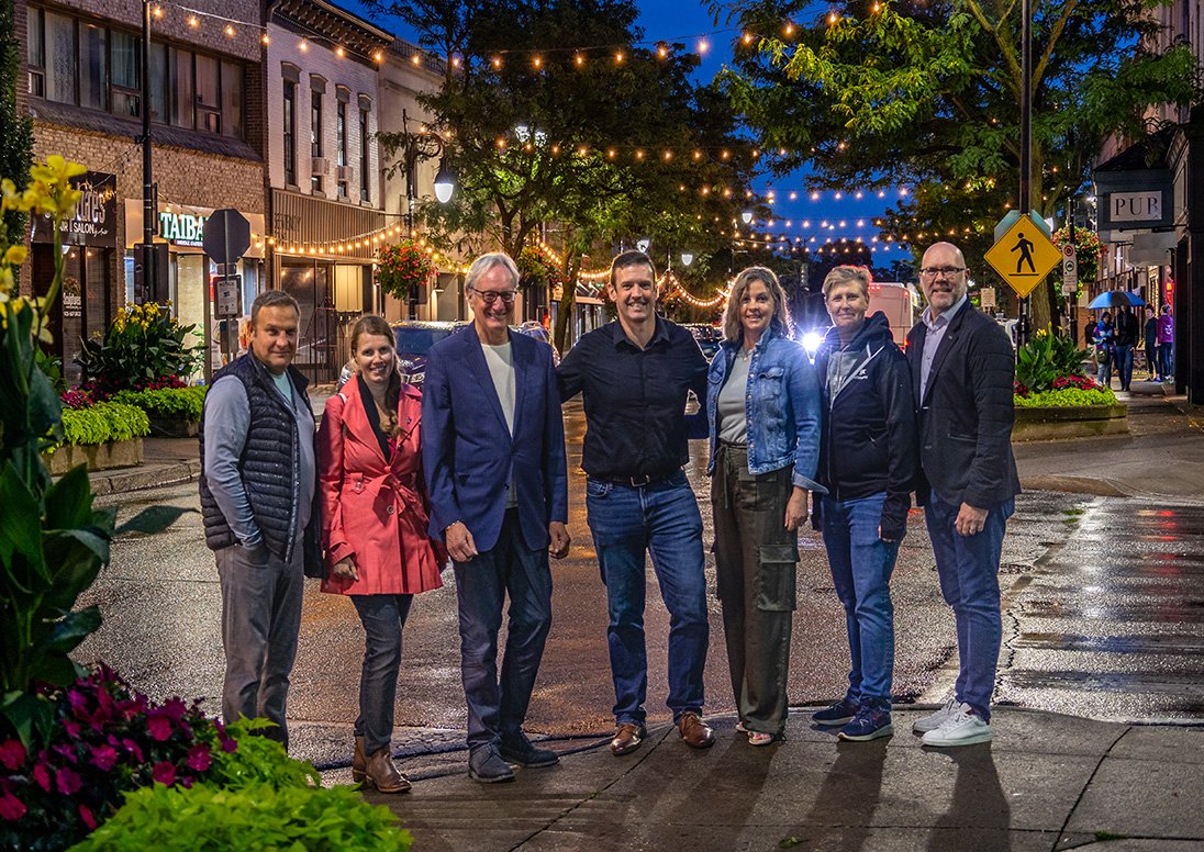 Representatives from the lighting project standing on a street corner on St. Paul Street in St. Catharines.. New lighting is visible in the background.