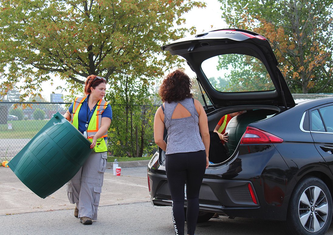 A City staff person loads a rain barrel into a St. Catharines resident's car.