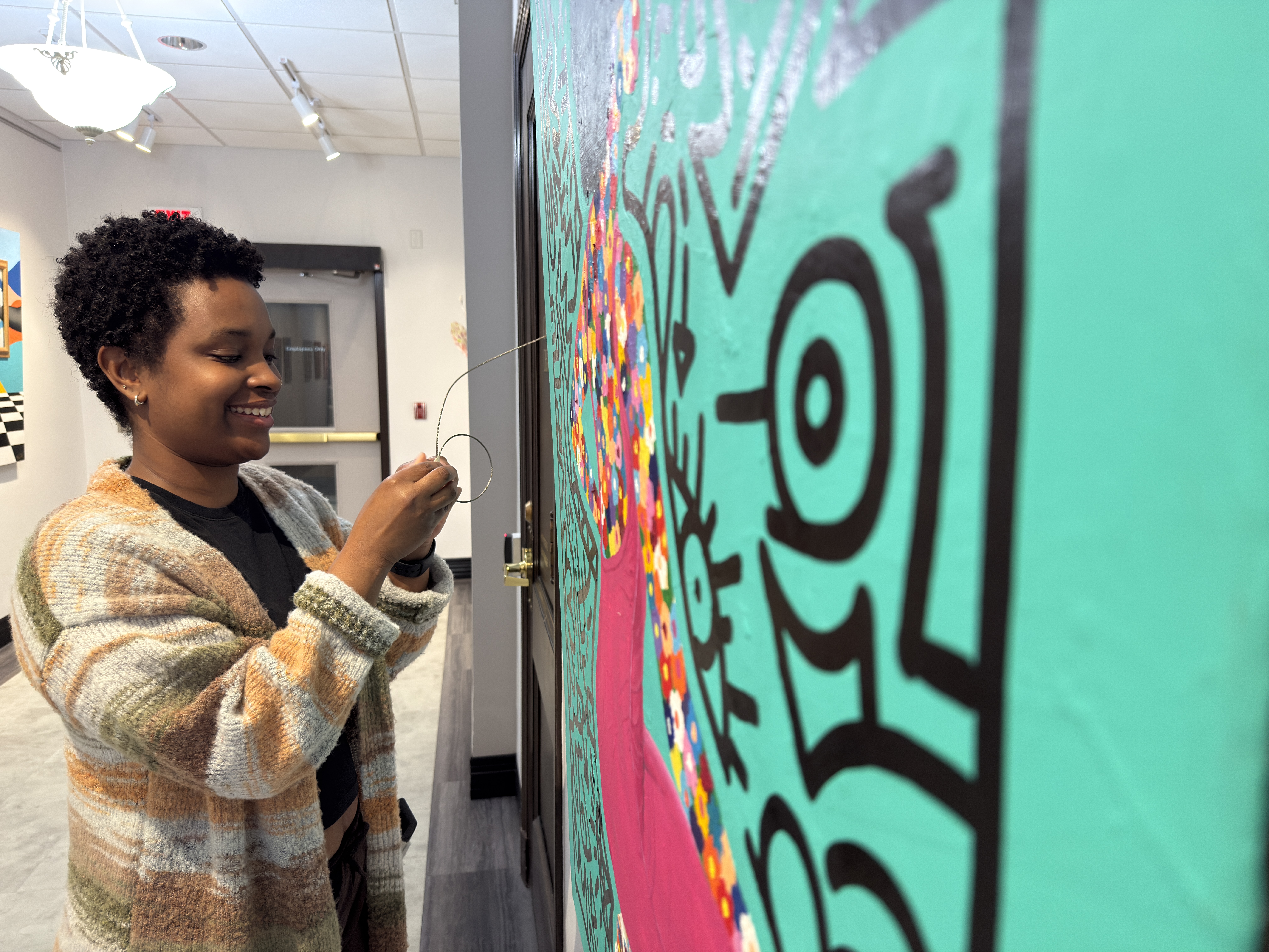 Tanika Hillocks hanging art from the Black Histories Black Futures exhibit at St. Catharines City Hall.