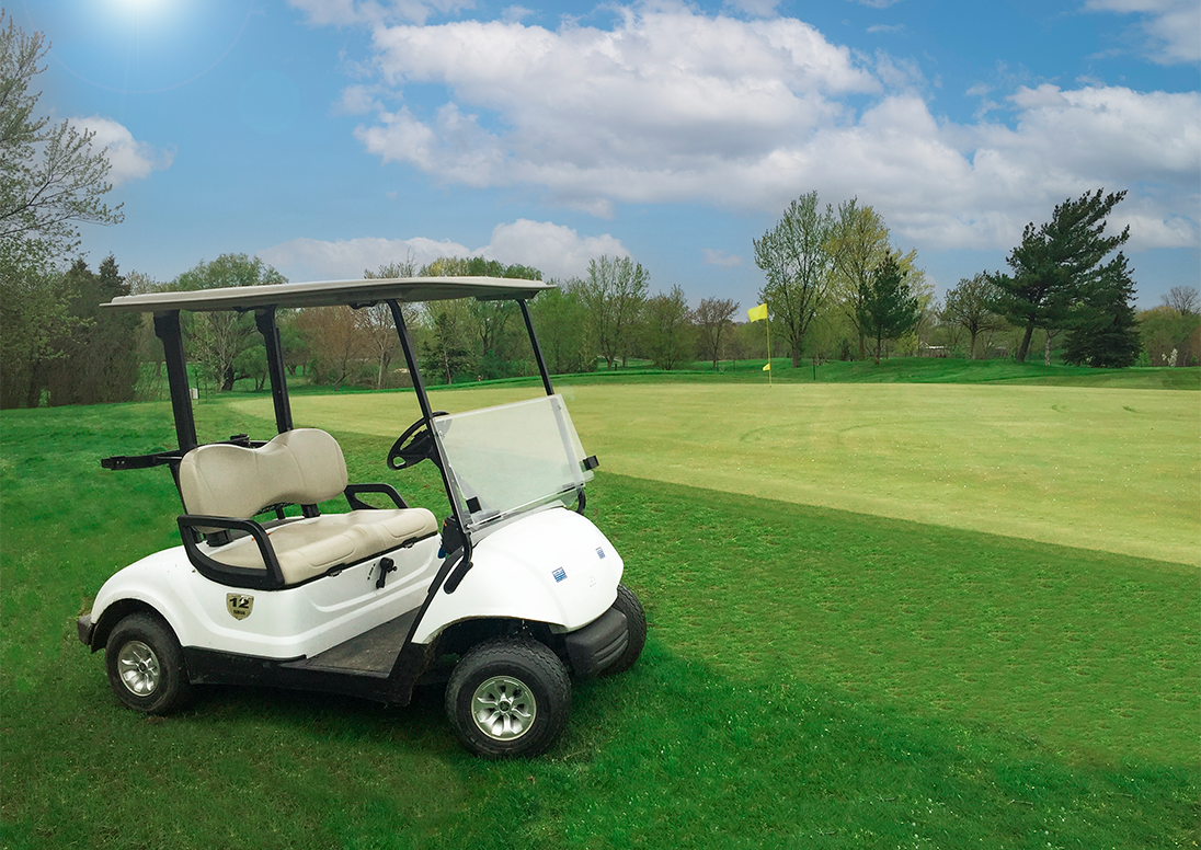 A motorized golf cart sits adjacent to a green on a golf course.