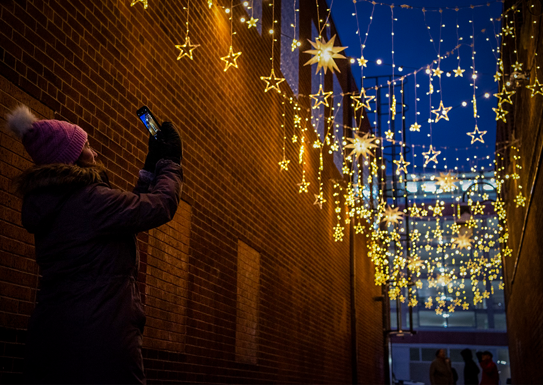 Woman taking picture of lights in alley