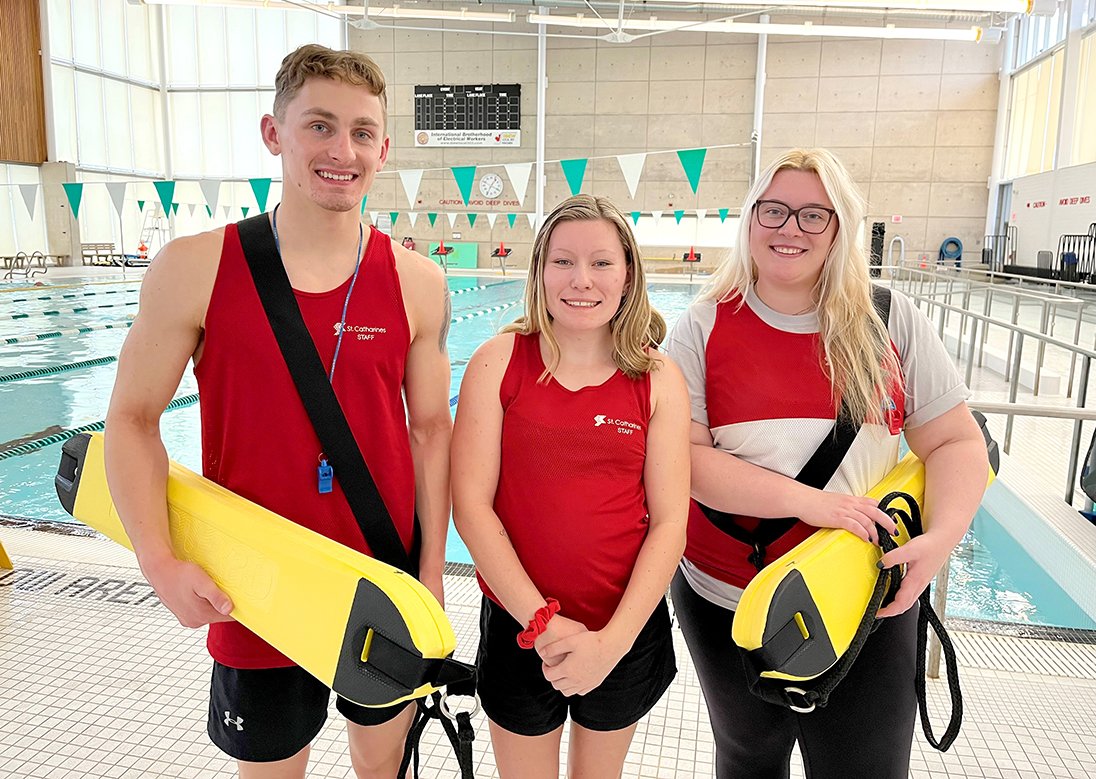 Three lifeguards standing in front of a pool