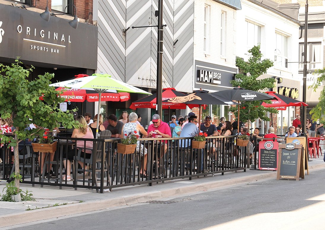A busy outdoor patio filled with people at a restaurant in downtown St. Catharines