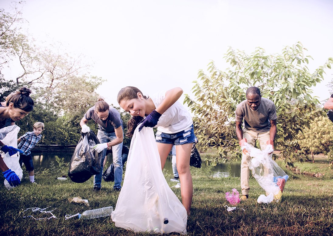 Individuals picking up garbage in a field