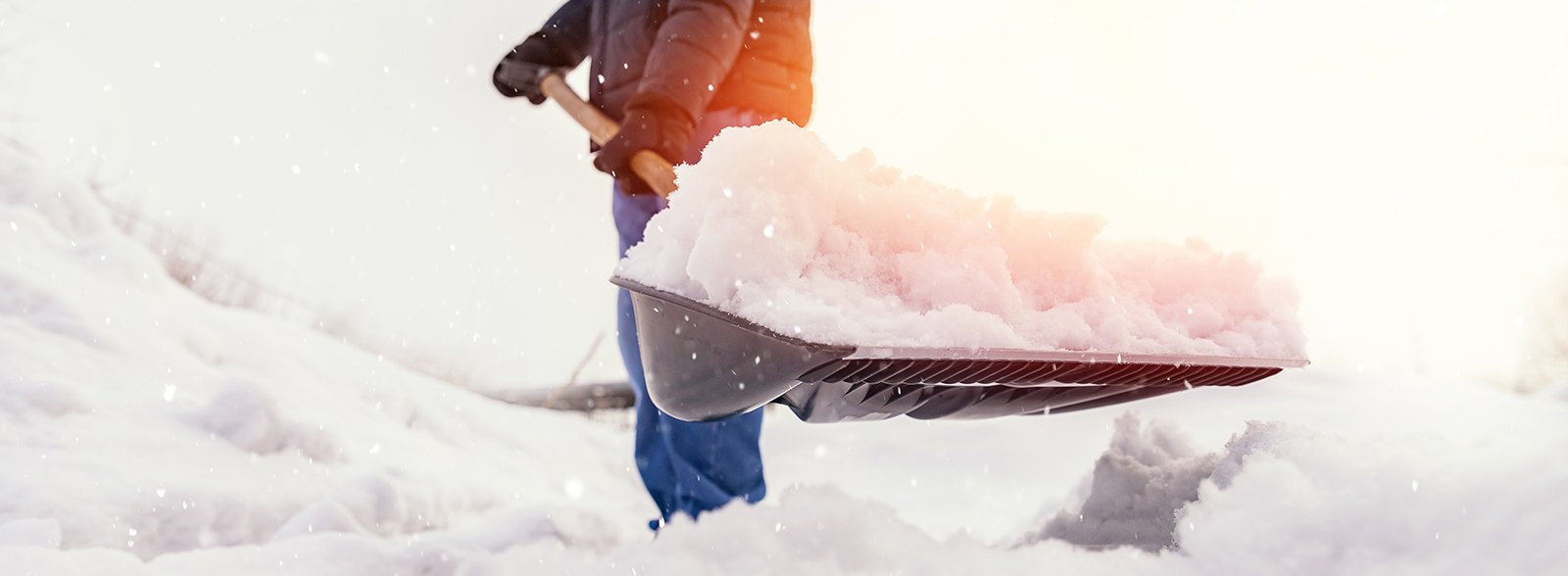 A shovel cuts throw a large mound of snow