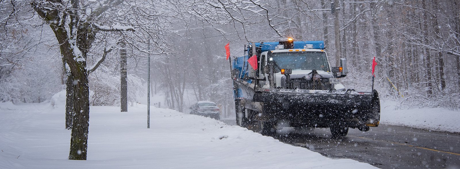 A snow plow clears snow on a City street