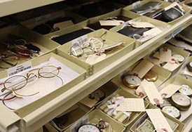 Artifact glasses and watches in boxes on a shelf.